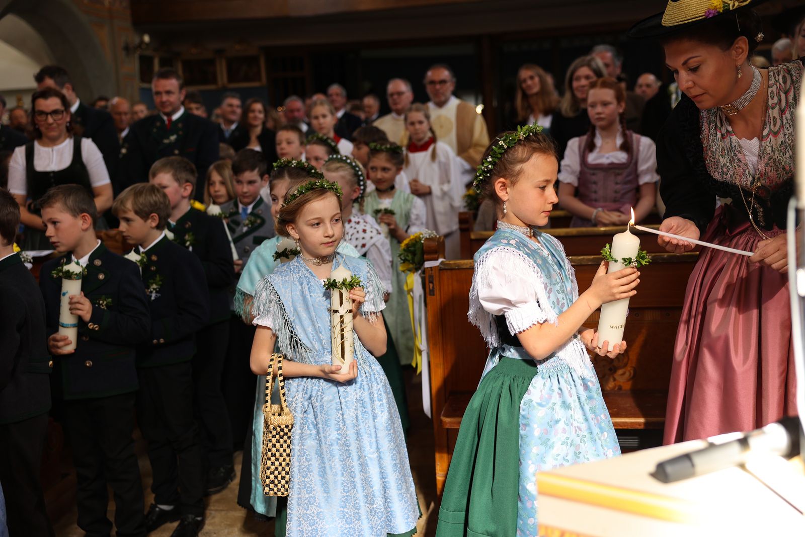 Die Kinder entzünden ihre Kommunionkerzen mit Hilfe von Müttern an der Osterkerze.