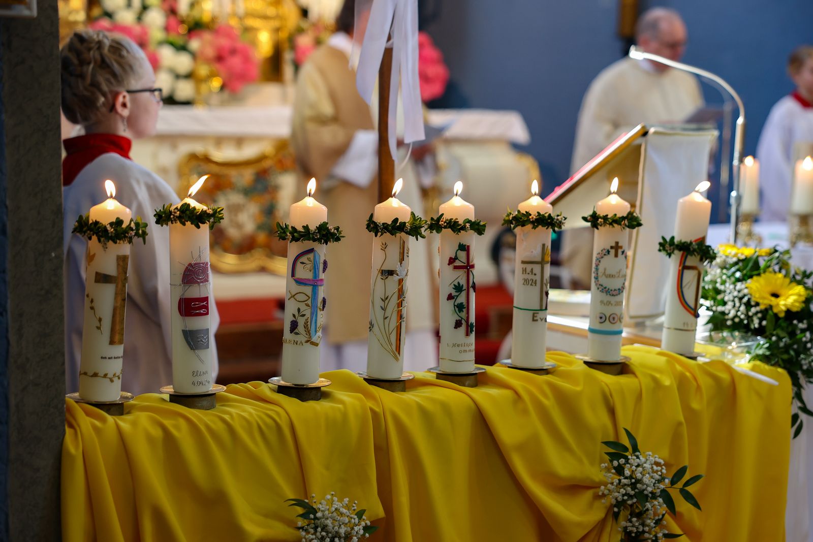 Die Kinder entzünden ihre Kommunionkerzen mit Hilfe von Müttern an der Osterkerze.