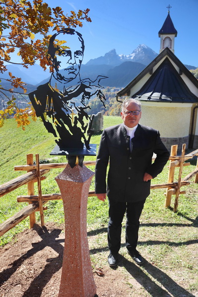 Pfarrer Msgr. Dr. Thomas Frauenlob neben der Stele am Ponnzenzenbichl